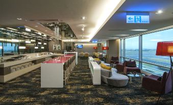 an airport lounge with a variety of seating options , including couches and chairs , as well as a television at Novotel Taipei Taoyuan International Airport