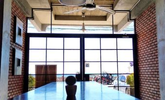 a long wooden table with a white cup on it in front of a window at The Bricks Hotel