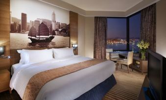 a spacious bedroom with expansive city views through large windows, featuring a comfortable bed positioned in the center at Harbour Grand Hong Kong