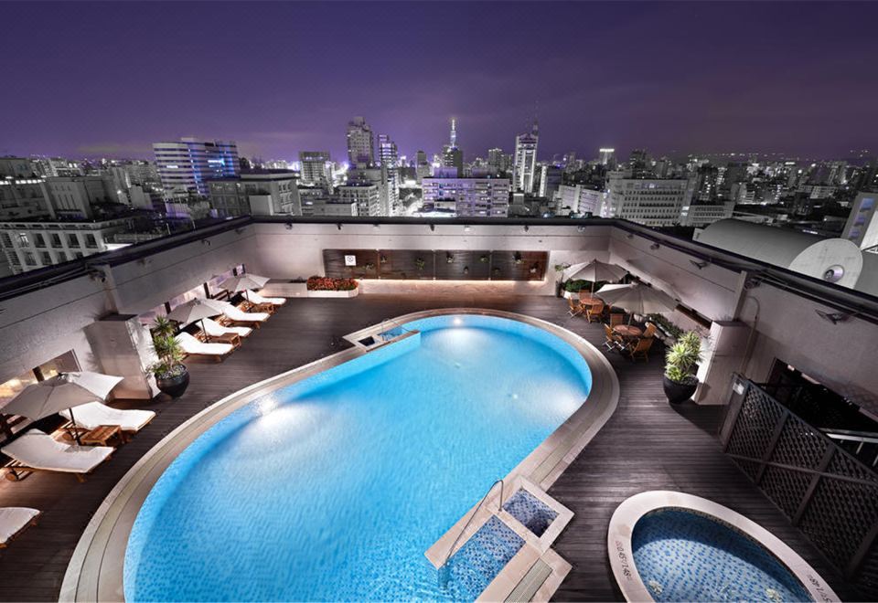 The upper floor bedroom offers a stunning city view at night, including a swimming pool on the roof at Sheraton Grand Taipei Hotel