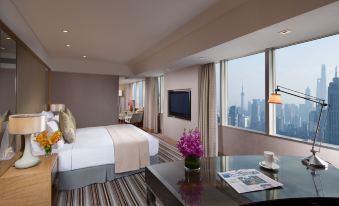 The bedroom features large windows and a centrally positioned bed, offering a picturesque view of the surroundings at Jin Jiang Tower
