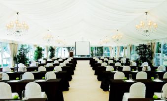 Rows of black chairs face the front of a large event space adorned with white tablecloths at Grand Coloane Resort Macau