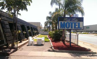 a blue and white motel sign is displayed in front of a building with palm trees at Lindy Lodge Motel