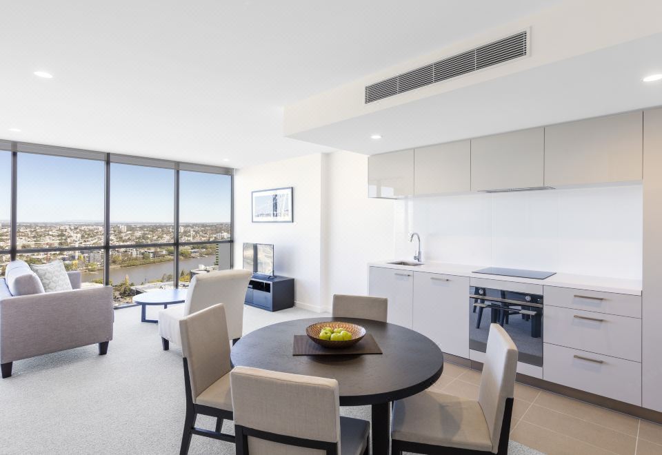 a modern kitchen with a dining table and chairs , as well as a view of the city outside the window at The Milton Brisbane