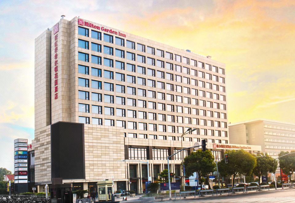 There is a large building with a visible exterior and a prominent name displayed in front at Hilton Garden Inn Shanghai Hongqiao NECC