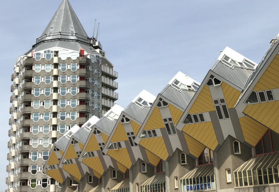 a modern building with unique triangular roof designs , situated in front of a tall apartment building at Hotel Emma