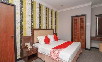 a well - arranged hotel room with a bed , nightstand , and lamp , along with green and white striped wallpaper on the walls at Garden View Hotel