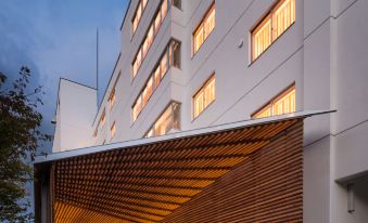 a modern building with wooden siding and a large window , illuminated by lights at night at WE Hotel Toya