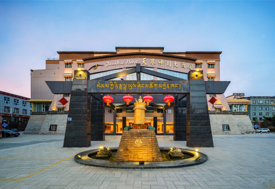 a large hotel entrance with a golden statue in the center and red lanterns hanging above it at Paradise Hotel