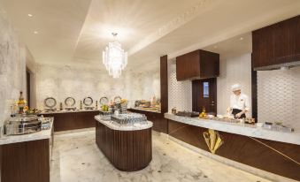 The open concept dining room features a kitchen counter filled with an abundance of food at Jinjiang Metropolo Hotel Classiq, Shanghai Bund Circle