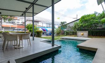 a modern house with a pool and patio area , surrounded by trees and parked cars at Viva Hotel Songkhla