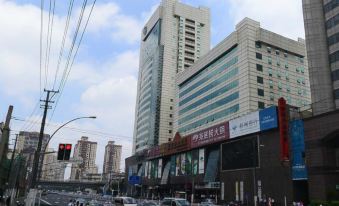 A large building with cars parked on the street in front and other buildings on both sides at Zhenyue Hotel