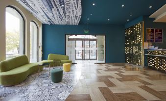 The lobby features blue walls and white painted wood paneling at Ibis Styles Hotel (Beijing Capital Airport)