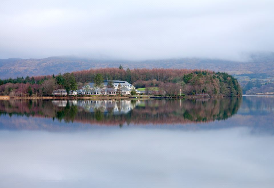 a serene scene of a lake surrounded by trees , with a building on the shore reflecting in the water at Harvey's Point