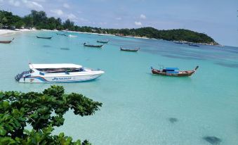 a group of boats are anchored in a clear blue ocean near a tropical island at Chareena Hill Beach Resort