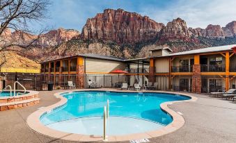 a large swimming pool is surrounded by a building and a mountain in the background at Best Western Plus Executive Residency Austin