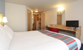 a clean and well - organized hotel room with a bed , a desk , a tv , and a refrigerator at Travelodge Kendal