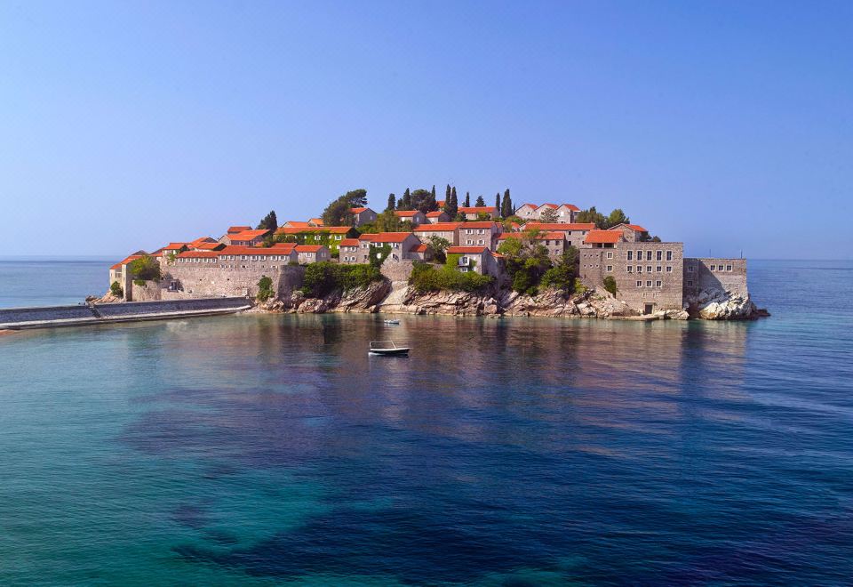 a serene view of a small island with orange - roofed buildings surrounded by clear blue water at Aman Sveti Stefan