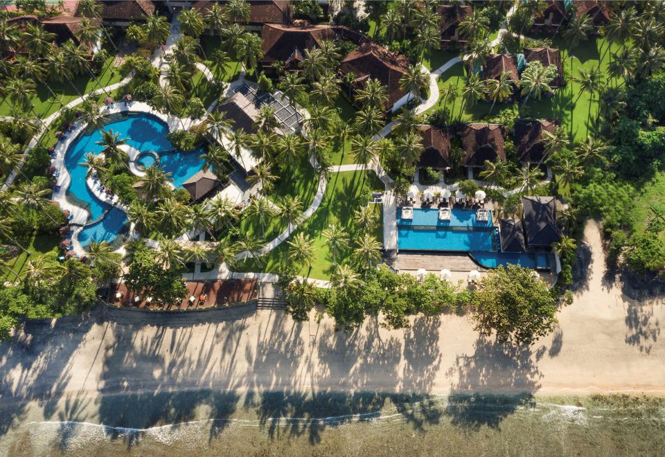 a bird 's eye view of a resort with palm trees , a pool , and a beach at Holiday Resort Lombok