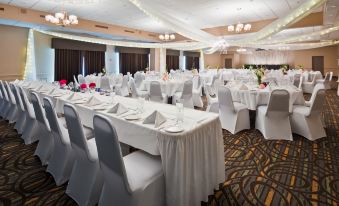 a large banquet hall with white tables and chairs , each set for a dinner party at Best Western Pembroke Inn  Conference Centre