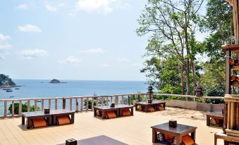 a wooden deck overlooking the ocean , with several tables and chairs set up for outdoor dining at Taatoh Seaview Resort