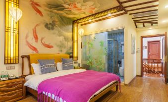 The bedroom features a spacious bed with a painting above it, accompanied by an elegant nightstand with a lamp, and a comfortable armchair in the corner at Zhouzhuang Latte Play Stone Mulan Hotel