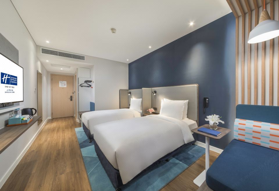 A contemporary bedroom on the top floor featuring a double bed and a spacious table in the center at Holiday Inn Express Shanghai Gubei