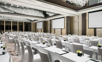 A spacious room is set up with rows of white tables for an event or function at The Langham Shanghai Xintiandi