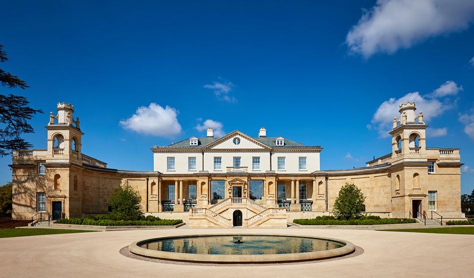 a grand house with a large courtyard and a fountain in front , under a clear blue sky at The Langley, a Luxury Collection Hotel, Buckinghamshire