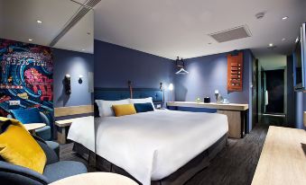 a large bed with white sheets is in a room with blue walls and furniture at Just Sleep Ximending