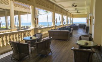 a large , empty hotel lobby with wooden floors and white walls , overlooking the ocean through large windows at Galle Face Hotel