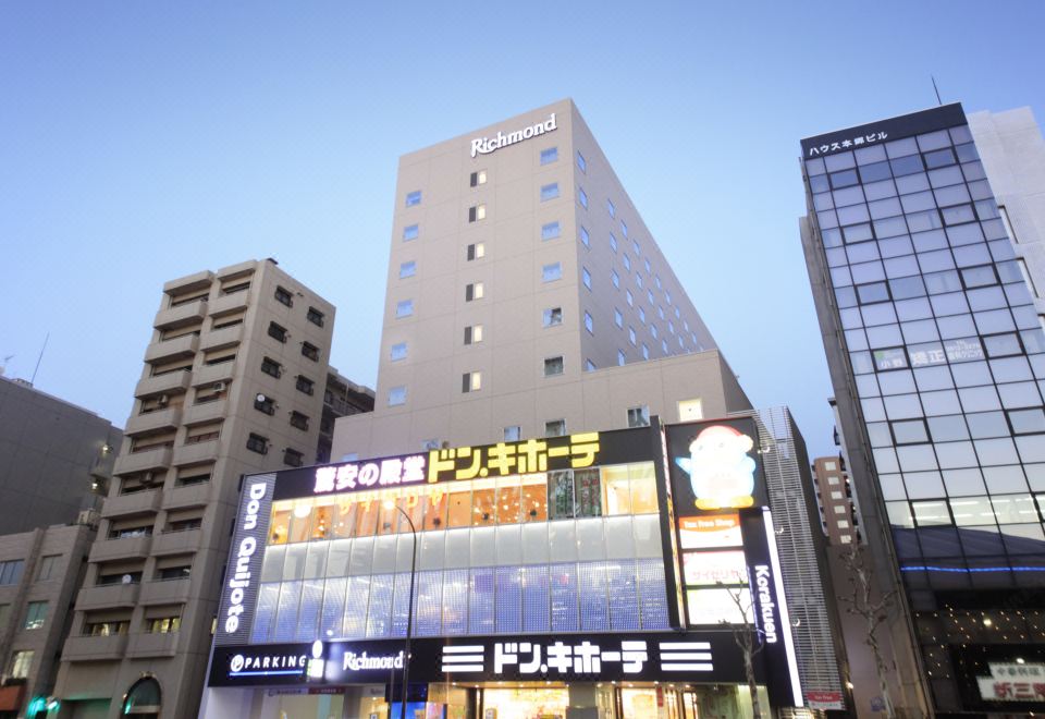 "There is a large building with a sign that says ""hotel"" in front, along with another sign" at Richmond Hotel Tokyo Suidobashi