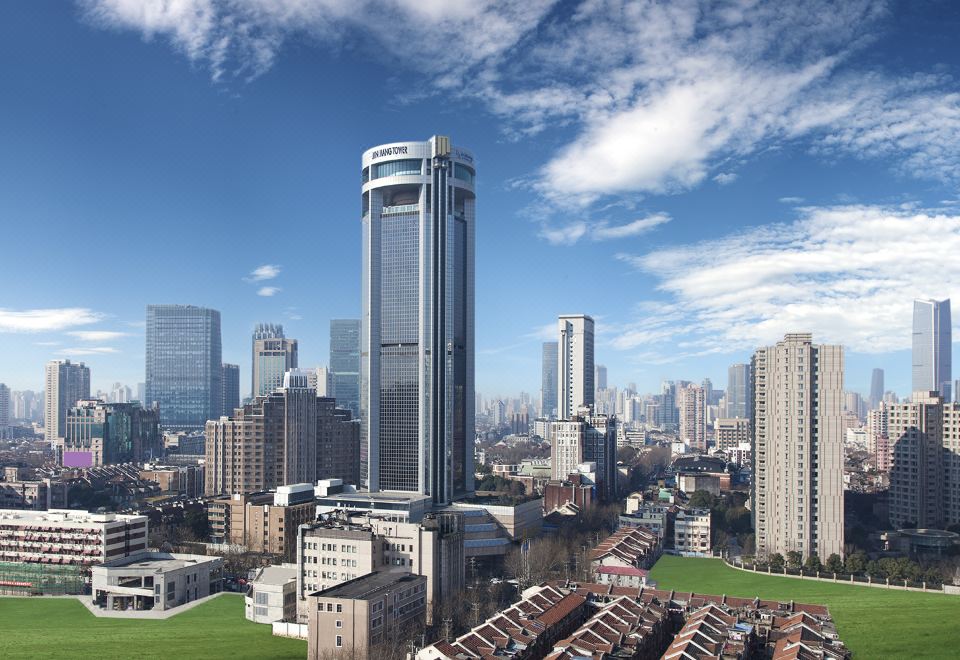 From a high vantage point, one can see a city with towering buildings and a prominent skyline in the foreground at Jin Jiang Tower