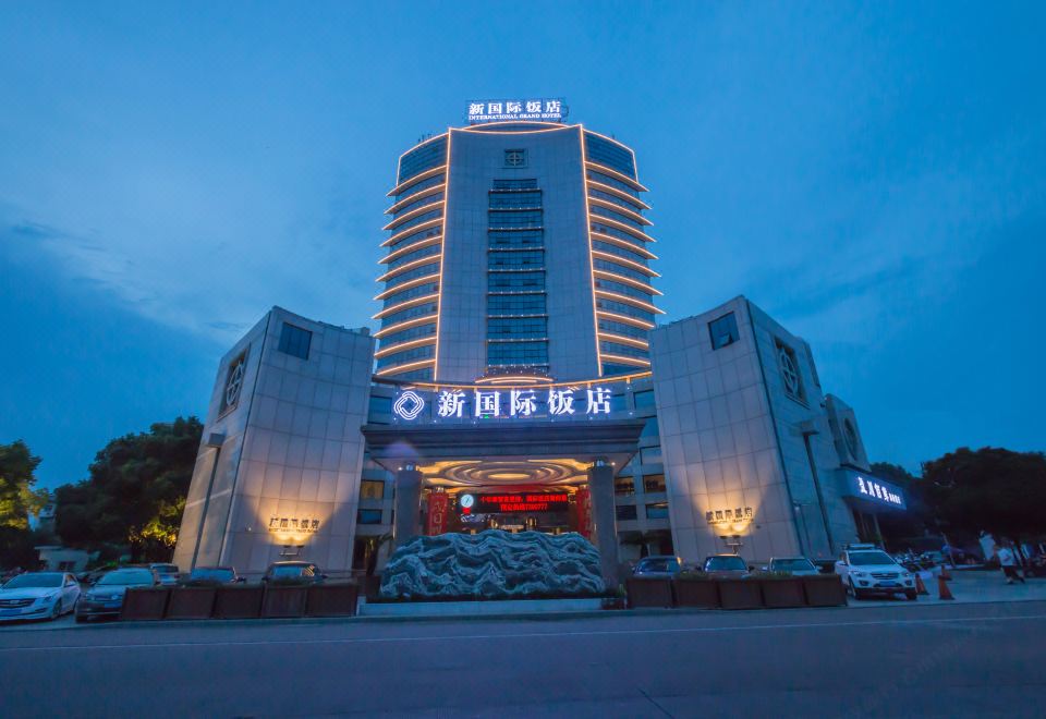 The building where a hotel is located is illuminated with neon lights at night at Longyou International Grand Hotel