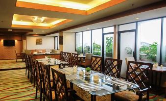 a well - lit restaurant with wooden chairs and tables , as well as large windows that offer views of the city at Planet Holiday Hotel & Residence