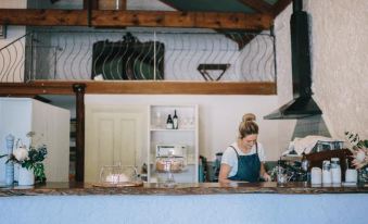 a woman wearing a blue apron is standing behind a counter in a bakery , preparing a cup of coffee at Terroir Auburn