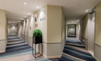 In this modern-style setting, there is a long hallway with carpeted floors and doors leading to other rooms at Home Inn Selected (South Square of Shanghai Railway Station)