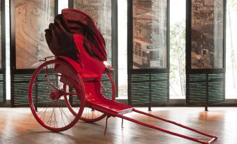 On the top floor, there is a middle room with a red chair, table, and an antique-style bed at Hotel Indigo Shanghai on The Bund