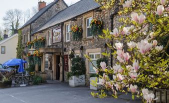 "a stone building with a sign that says "" the downs inn "" is adorned with flowers" at George Inn