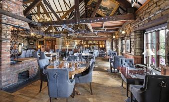 a large dining room with wooden floors , high ceilings , and stone walls , filled with people sitting at tables and enjoying their meals at The Cook and Barker Inn