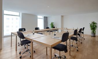 There is an empty conference space at the far end that contains a meeting room with large tables and chairs at base SUHE Serviced Apartment