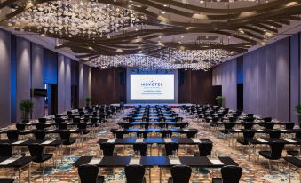 A spacious room with tables and chairs is arranged for hosting events or conferences at Novotel Shanghai Hongqiao