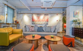 The room is decorated to resemble an outdoor space, with tables, chairs, and couches arranged in the center at Yuzhan No.8 Art Hotel (Shanghai Beach Branch)