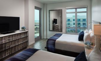 a modern hotel room with two beds , a television , and large windows overlooking the city at Treasure Island Beach Resort