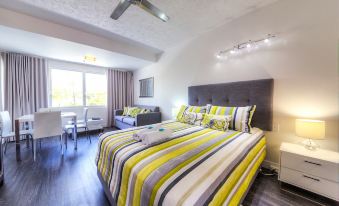 a large bed with a yellow and gray striped blanket is in a room with a couch , chairs , and a dining table at Rosslyn Bay Resort