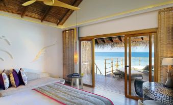 a bedroom with a large bed and sliding glass doors leading to a balcony overlooking the ocean at Constance Moofushi