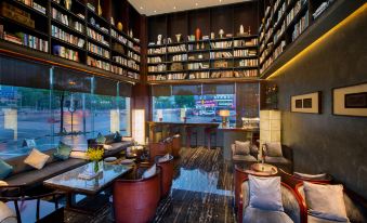 A room with tables, large windows, and bookshelves filled to the side at Kasion Purey Hotel (Yiwu International Trade City store)