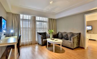 a spacious living room with a couch , coffee table , and large windows that offer views of the city at Relax Hotel