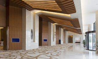 a modern hotel lobby with marble floors , wooden ceiling panels , and a reception desk , providing a clean and professional atmosphere at Sheraton Qinhuangdao Beidaihe  Hotel