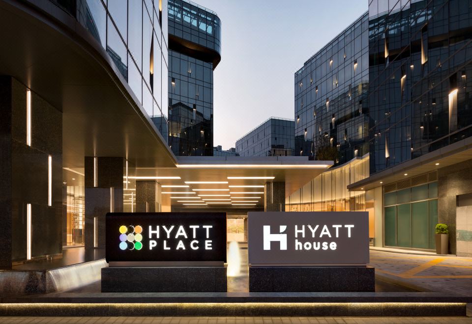 The entrance to an office building is marked by a sign, with other buildings located behind it at Hyatt Place Shanghai Hongqiao CBD